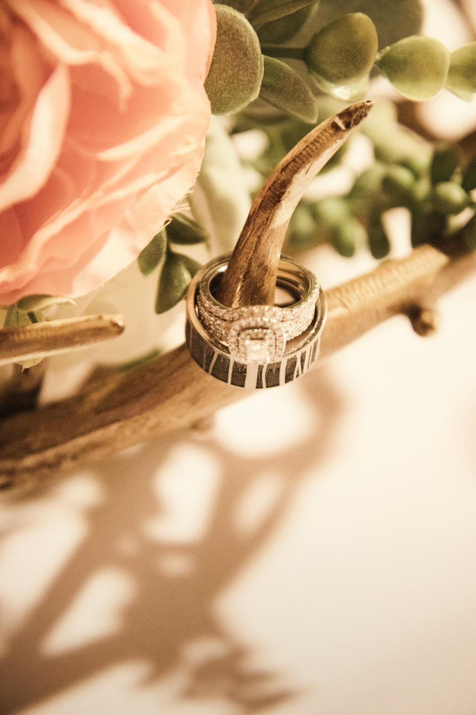 Diamond engagement and wedding rings on wood with flowers.