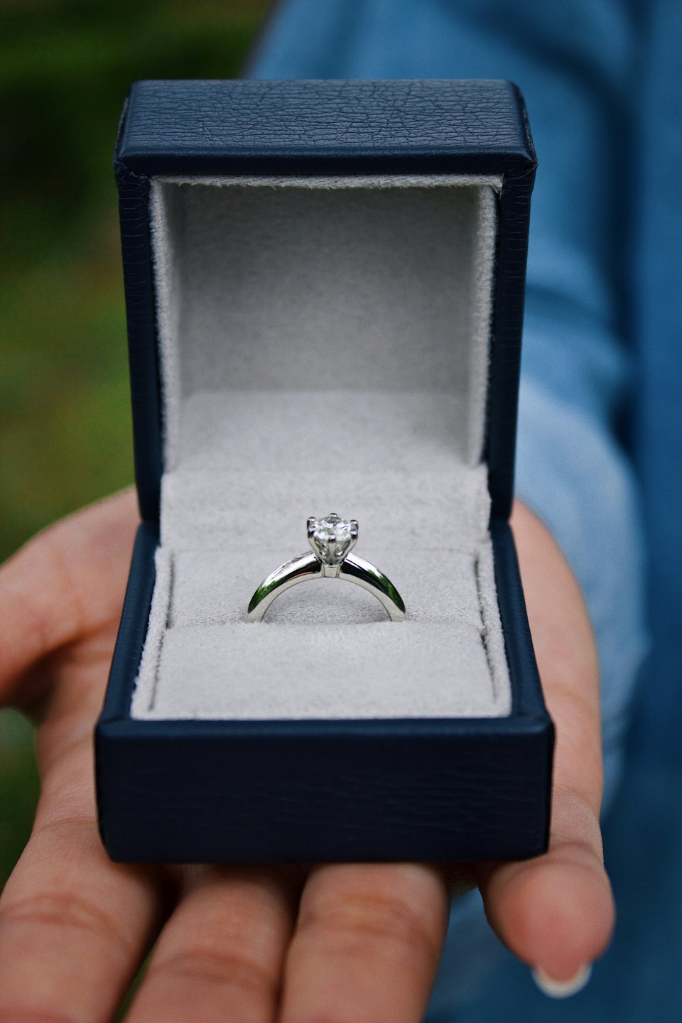 Navy blue velvet box presents diamond engagement ring.