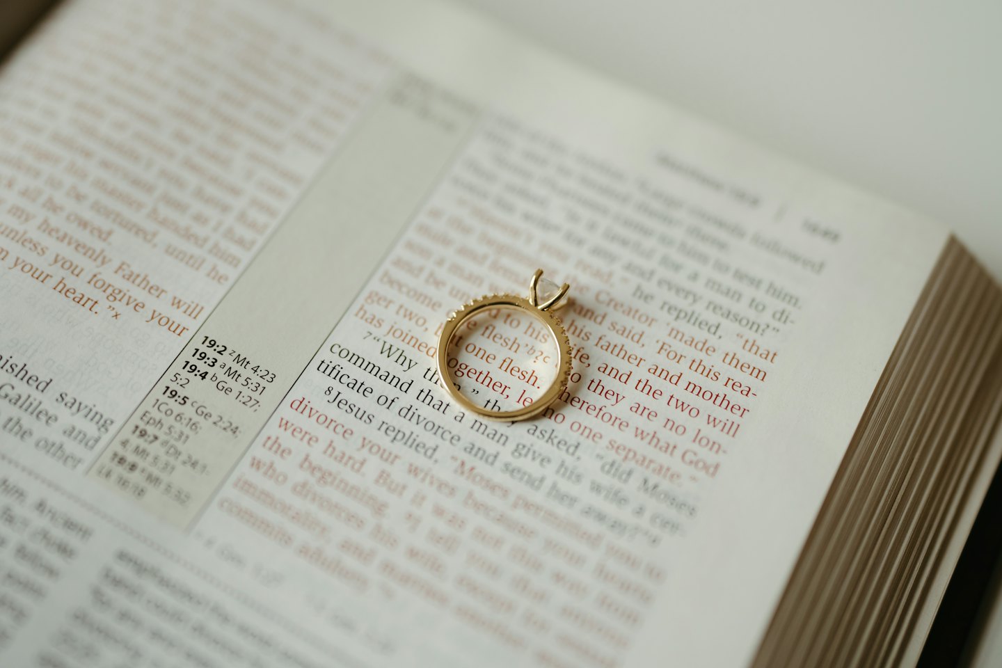 A diamond ring sits on an open page of a Bible.