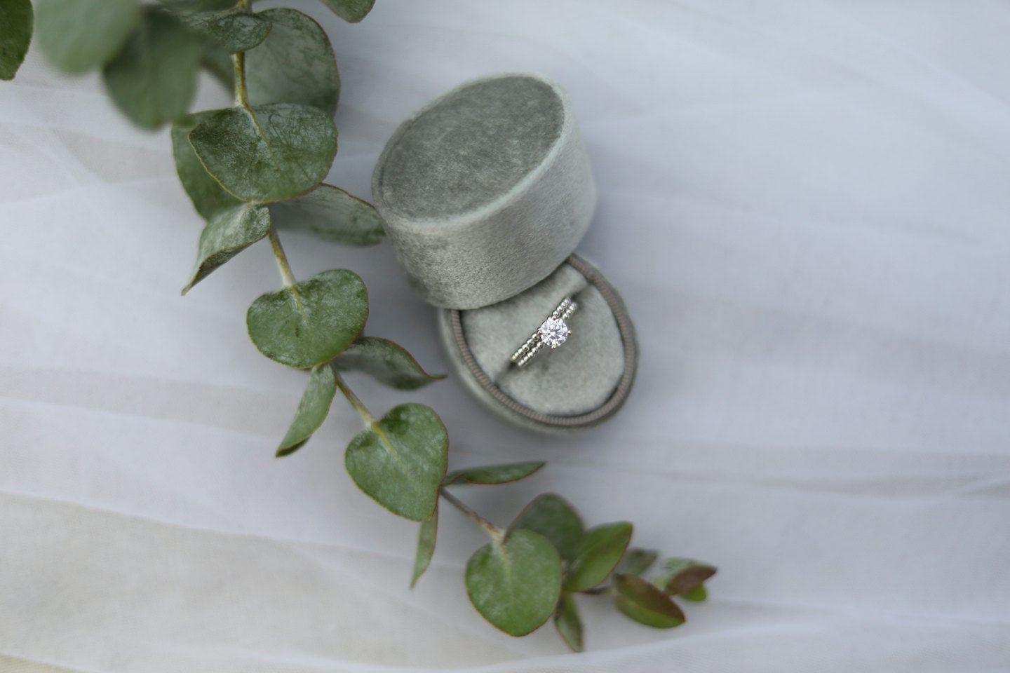 Silver engagement ring and wedding band in a sage green velvet box.