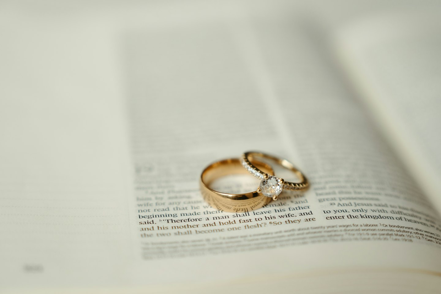 Gold and diamond rings resting on open book pages.